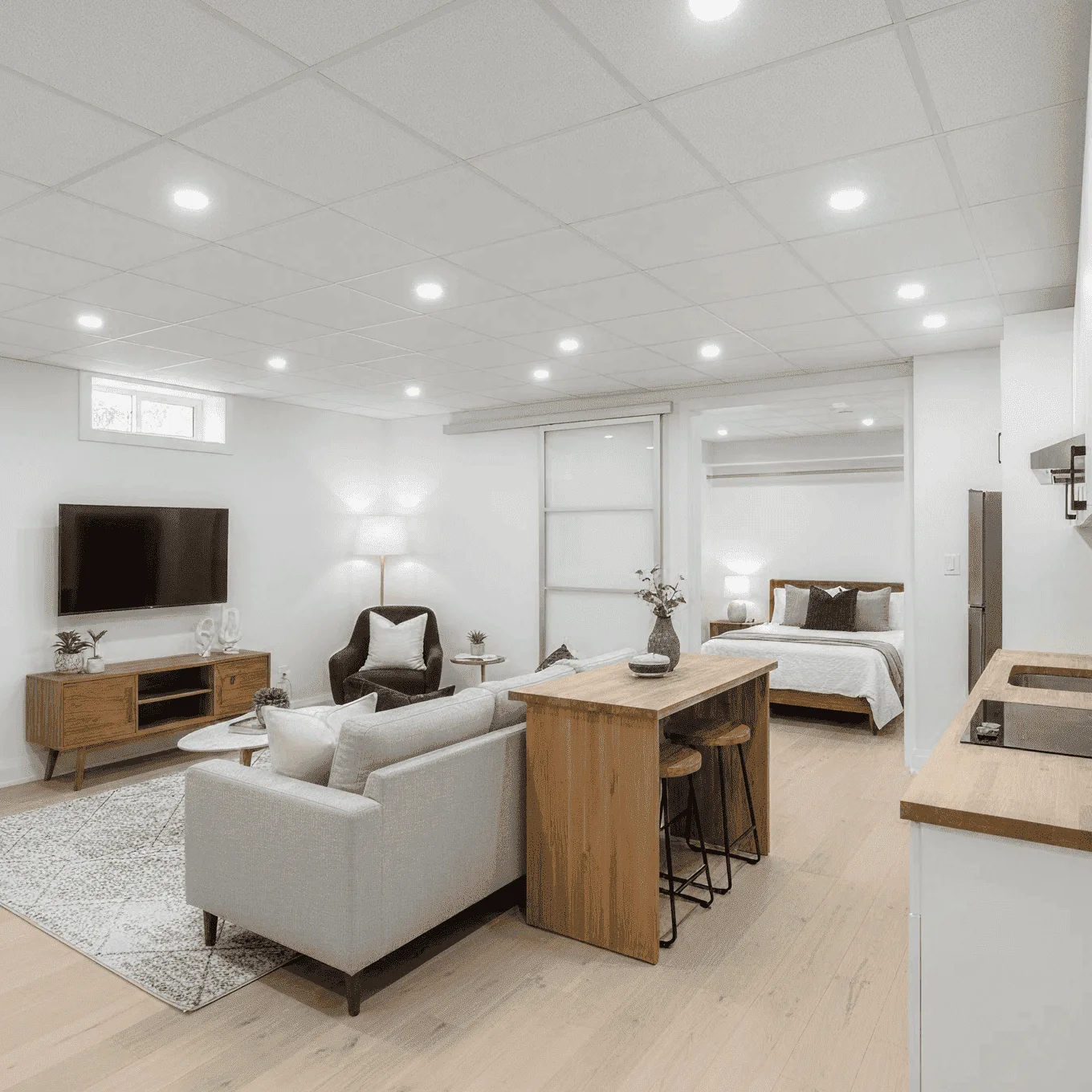 Finished basement renovation in Westchester, NY featuring cozy lounge with sectional sofa, built-in bookshelves, and entertainment area.