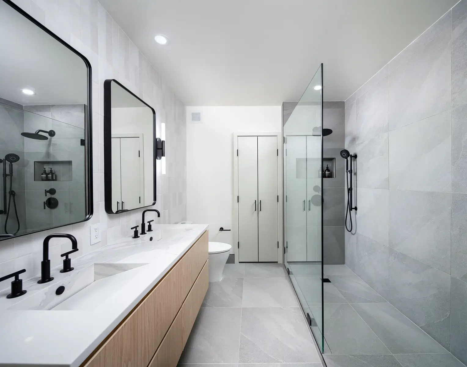 Finished NYC bathroom renovation with custom vanity, stone tile, brass fixtures, and walk-in shower