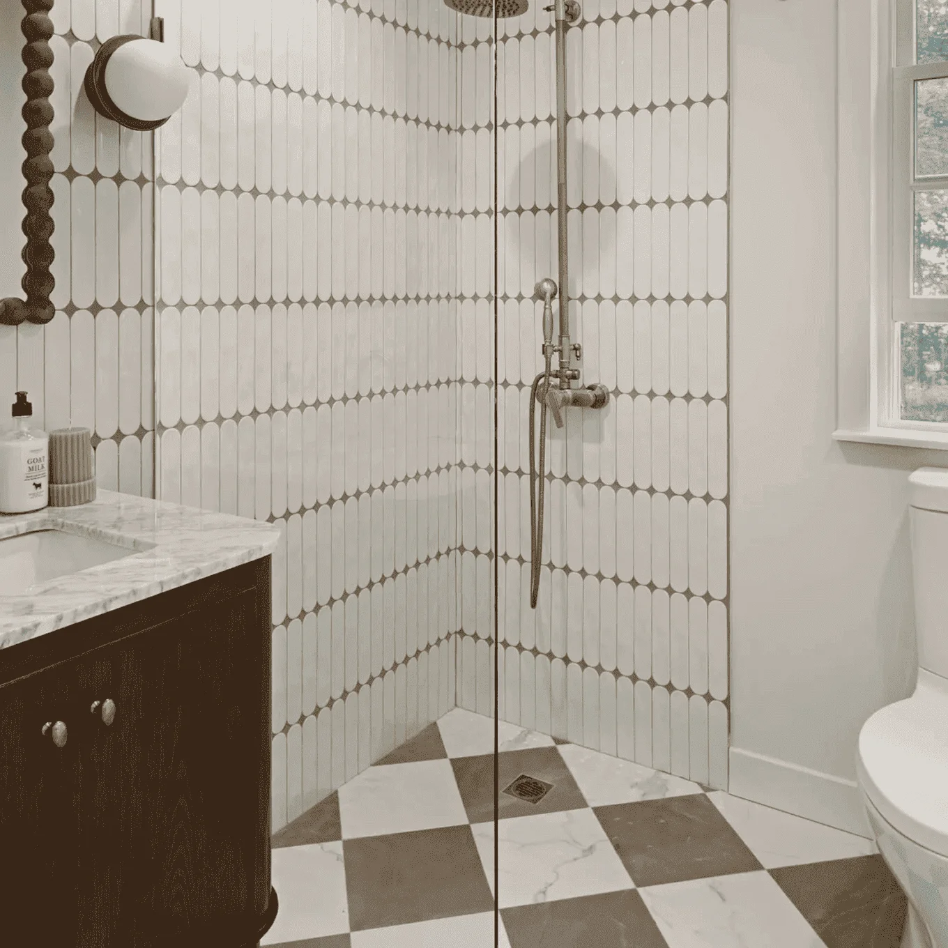 Bathroom with vertical white subway tiles, checkered floor, marble vanity, and brass shower fixtures in New Rochelle, Westchester, NY.