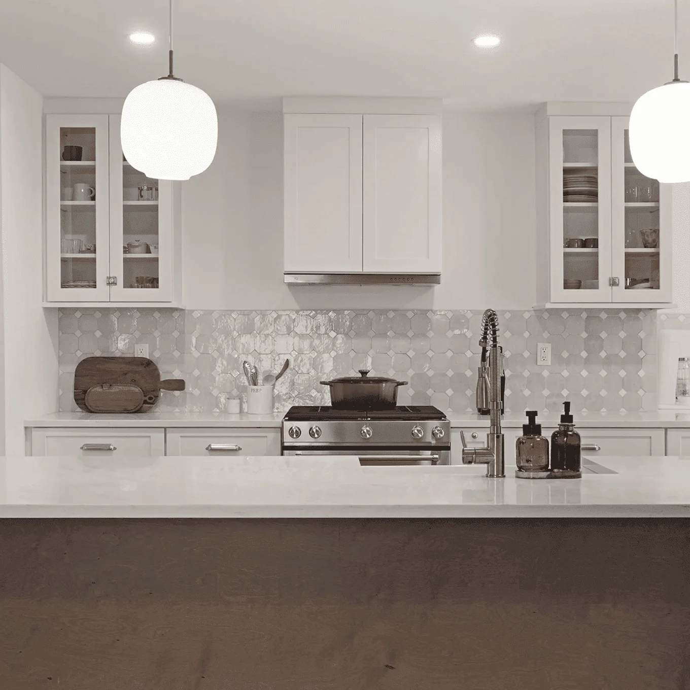 Modern kitchen in New Rochelle with white shaker cabinets, marble island, stainless range, hex-tile backsplash and pendant lights.