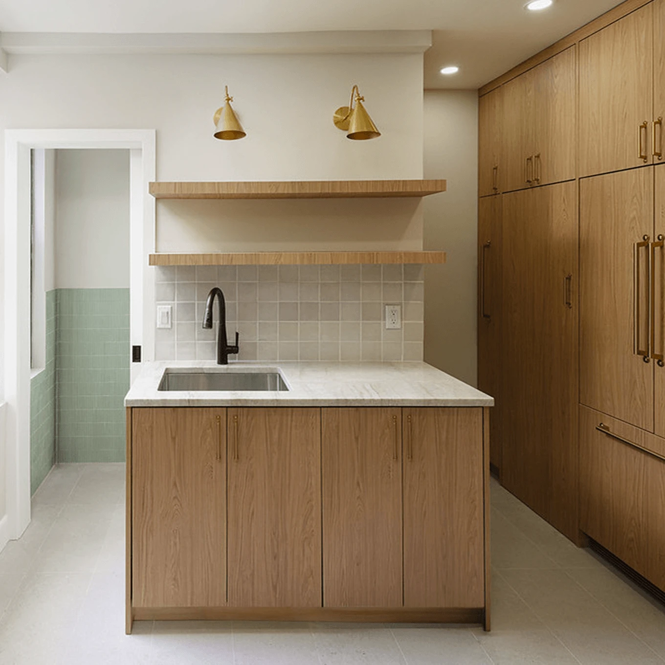 Modern kitchen with light oak cabinets, a marble island, and brass accents after a gut renovation