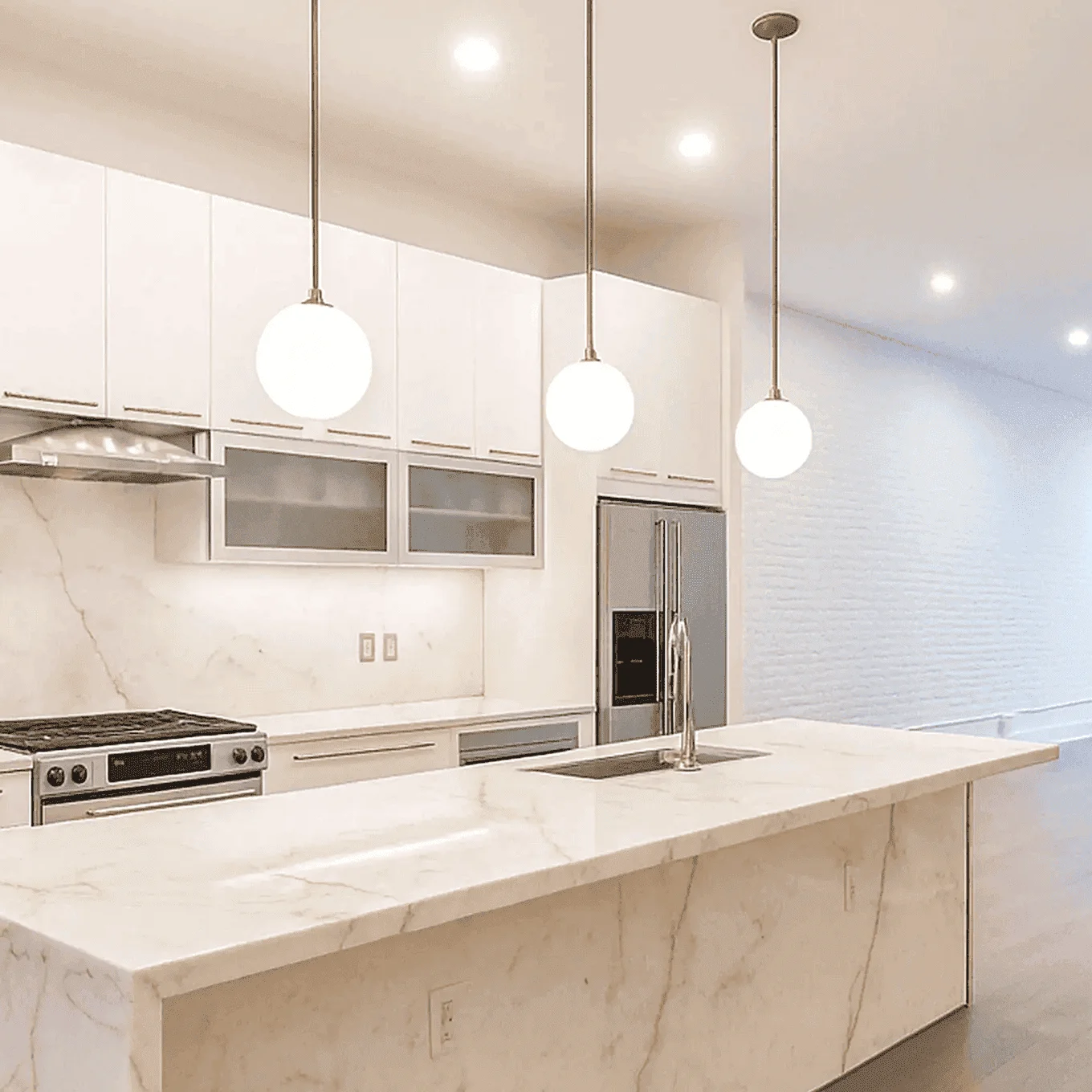 Open-concept kitchen and living area featuring white cabinets, marble waterfall island, globe pendant lights, and wide-plank floors, part of a complete apartment renovation on Somerset ln, Edgewater, New Jersey