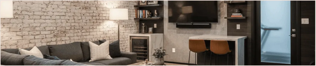 Basement media room transformation with exposed brick walls, sectional sofa, and built-in entertainment unit — renovation by Chapter.
