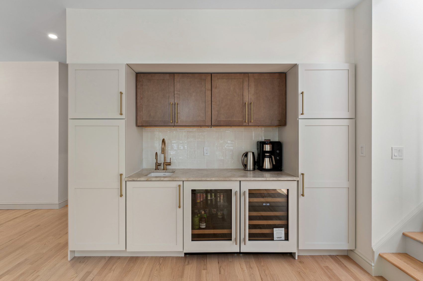 Finished beverage station with custom cabinetry, wine refrigerator, beverage refrigerator, and stone backsplash.