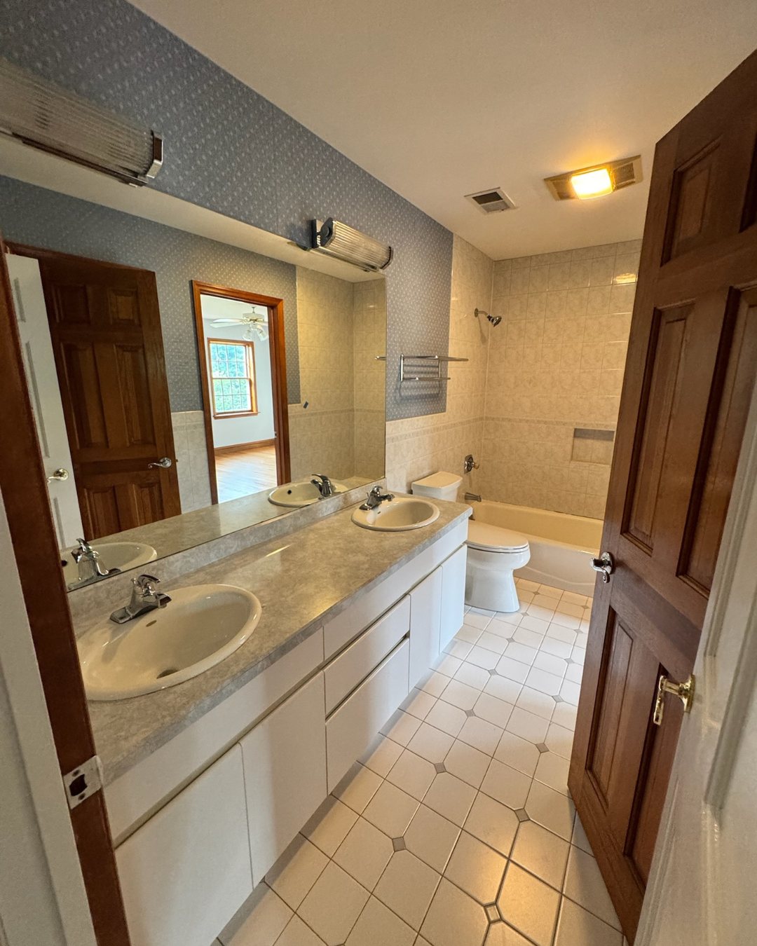 Before view of the kids bathroom with older vanity, tub, and finishes.