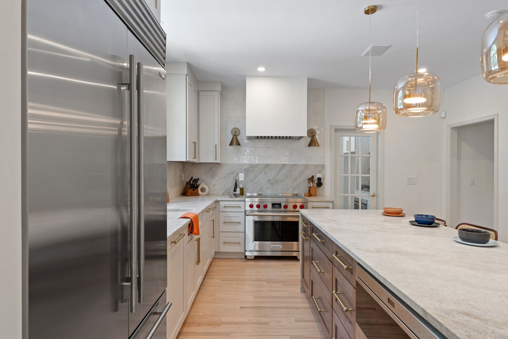 Renovated kitchen with large island, integrated refrigerator, quartzite counters, and wood cabinetry.