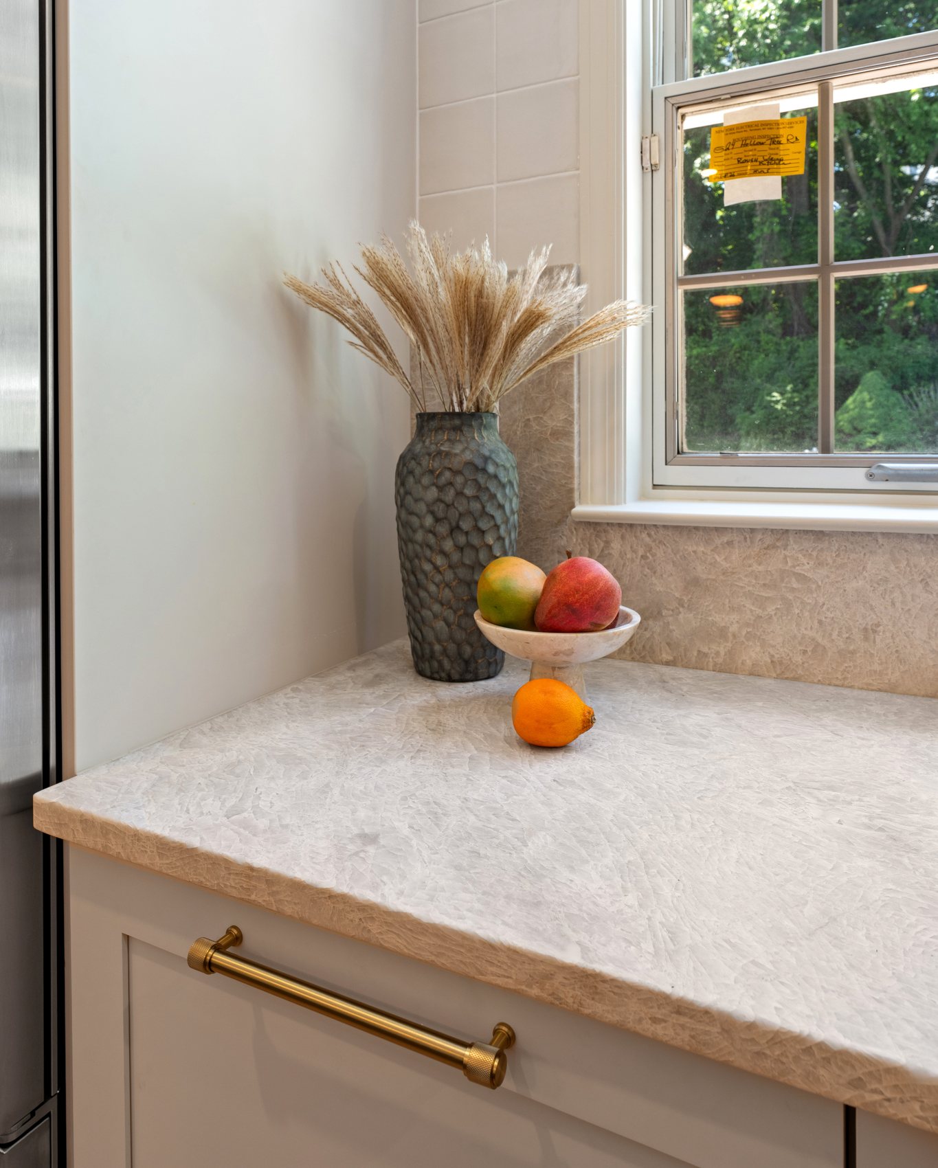 Close view of Taj Mahal quartzite counter surface and brass cabinet hardware.