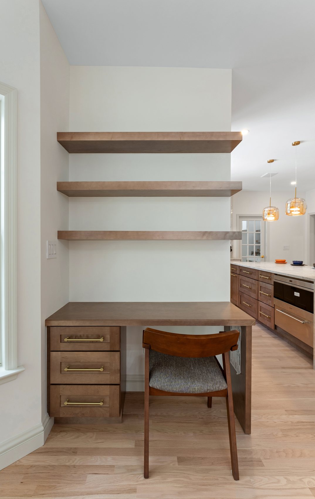 Custom built-in workspace with open shelving, drawers, and light oak flooring.