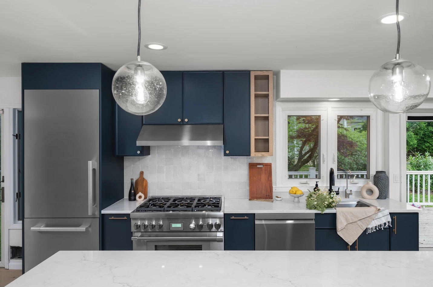 Renovated Rye kitchen with custom deep blue solid wood cabinetry, oversized quartz island, and concealed appliance storage