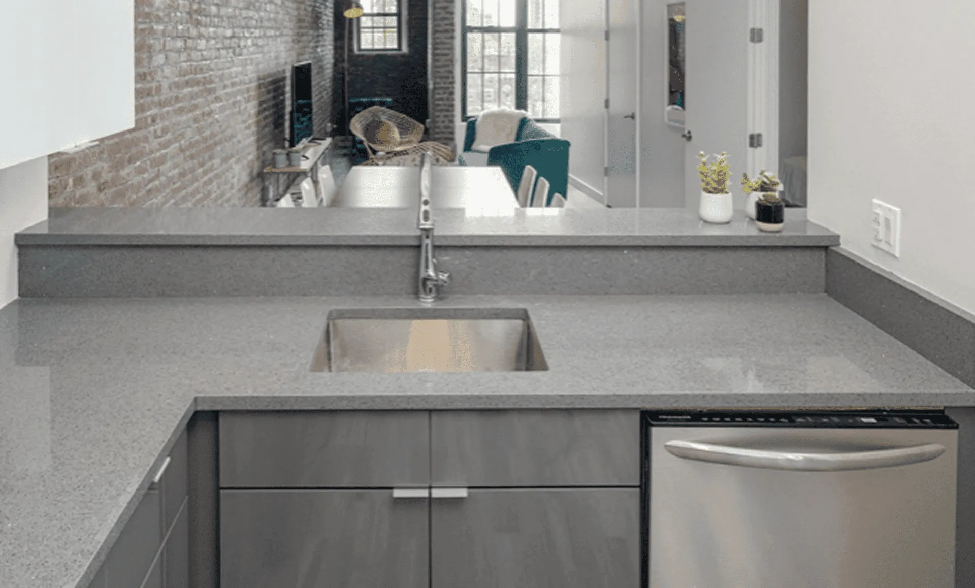 Gray quartz peninsula with undermount sink overlooking dining and living areas in renovated Jersey City loft.