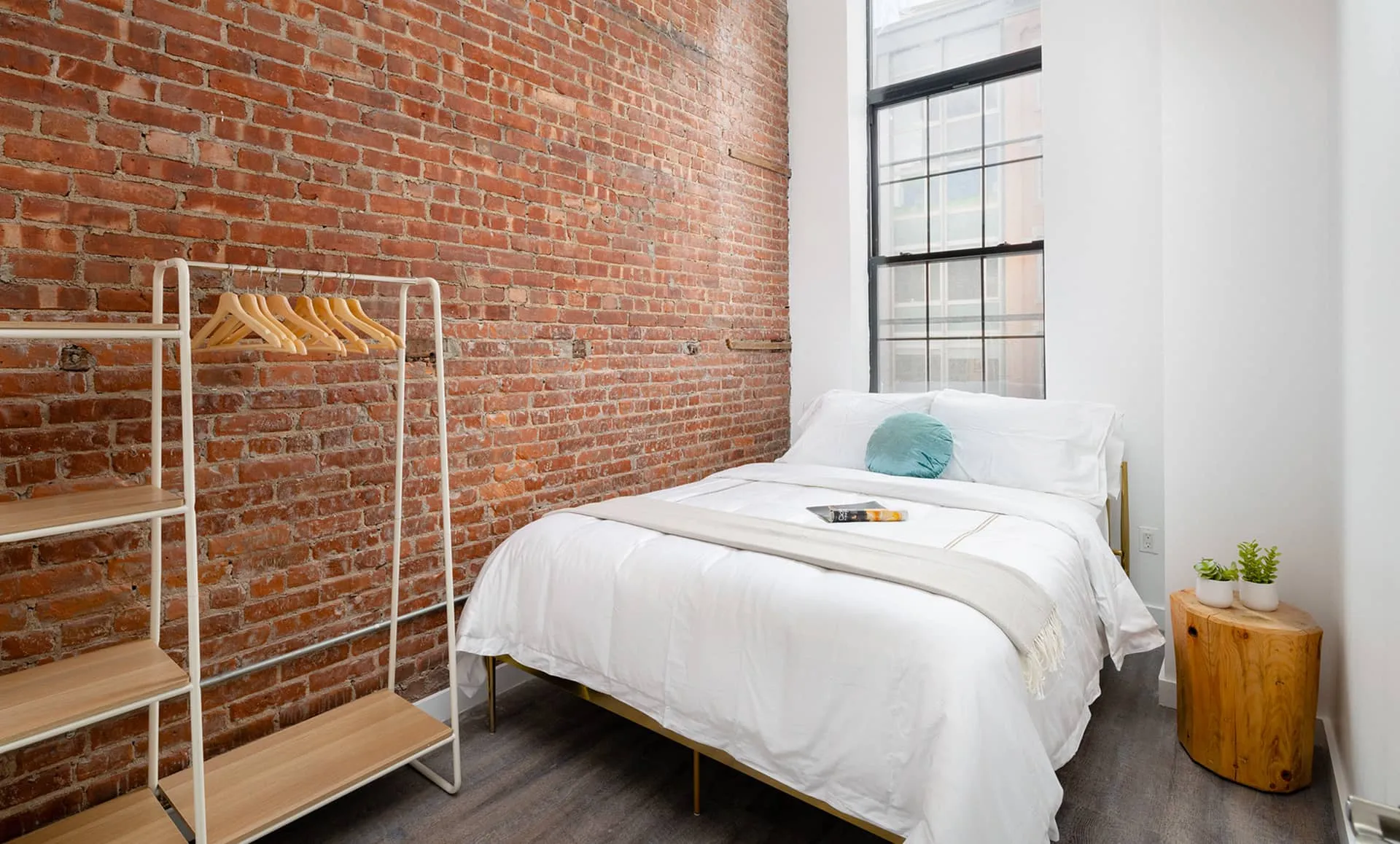 Bedroom with exposed brick wall, modern furniture and contemporary design in Jersey City apartment