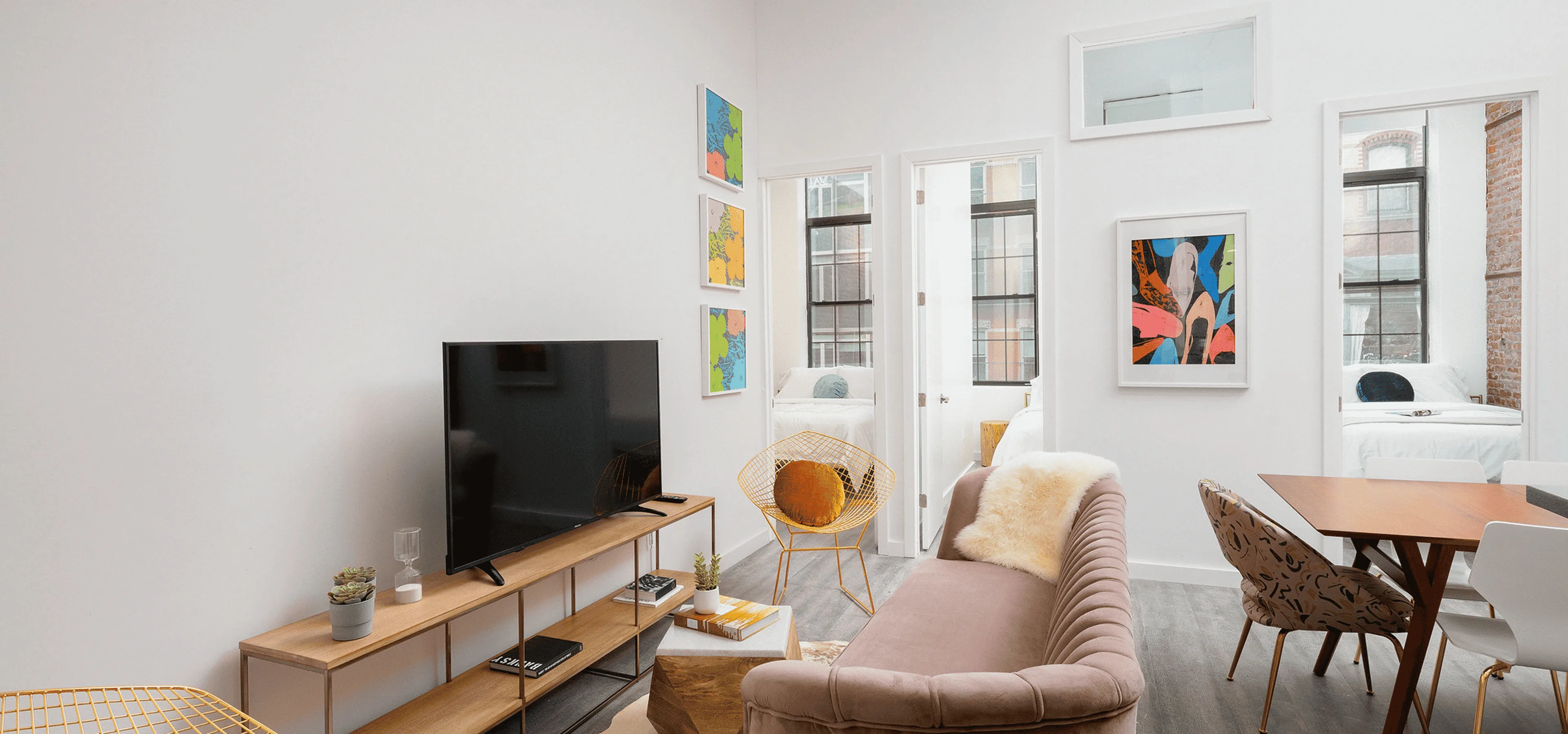 Bright Jersey City living room with pink sofa, yellow accent chairs, colorful art.