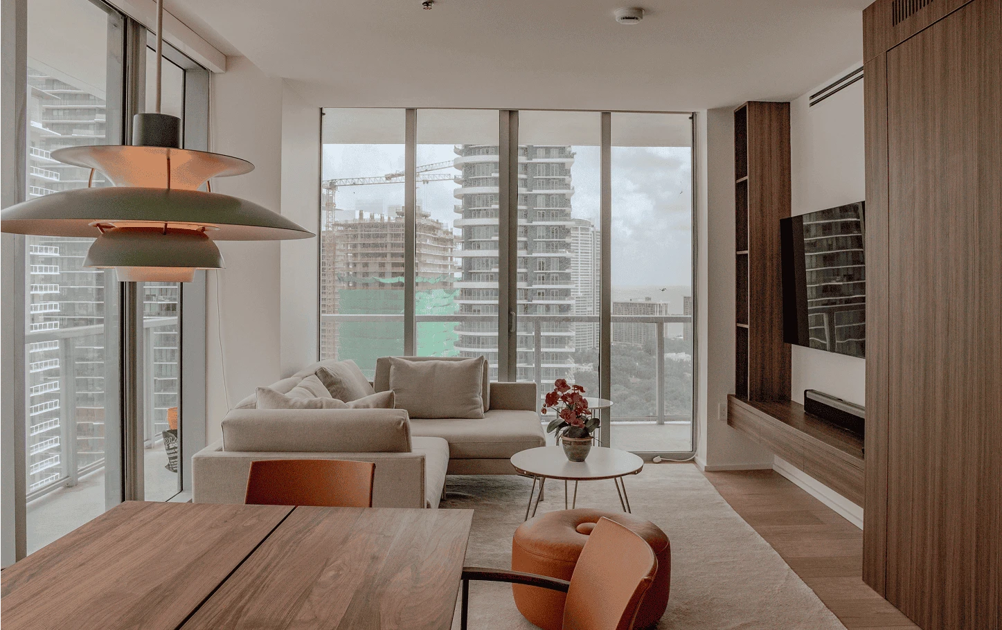 Living and dining area of a renovated Axis Brickell condo featuring custom wood millwork, floor-to-ceiling windows, and modern Scandinavian-inspired furnishings.