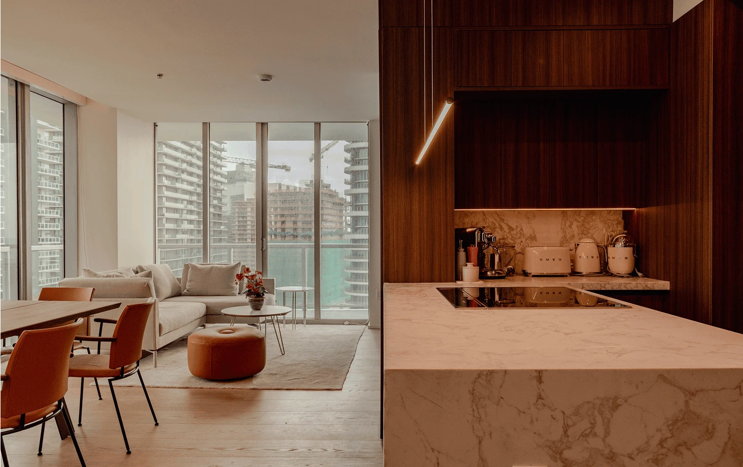 Open kitchen and living area in a renovated Axis Brickell condo, featuring marble countertops, wood cabinetry, and floor-to-ceiling windows overlooking the Miami skyline.
