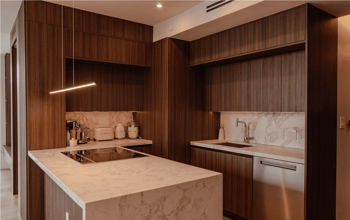 Contemporary kitchen in the Axis Brickell condo featuring marble countertops, oak millwork, and concealed appliances for a seamless modern look.