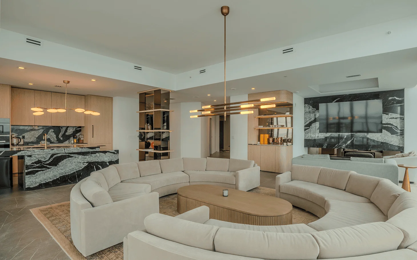 Luxurious open-concept kitchen and living space with marble countertops, custom millwork, and contemporary lighting in Miami condo