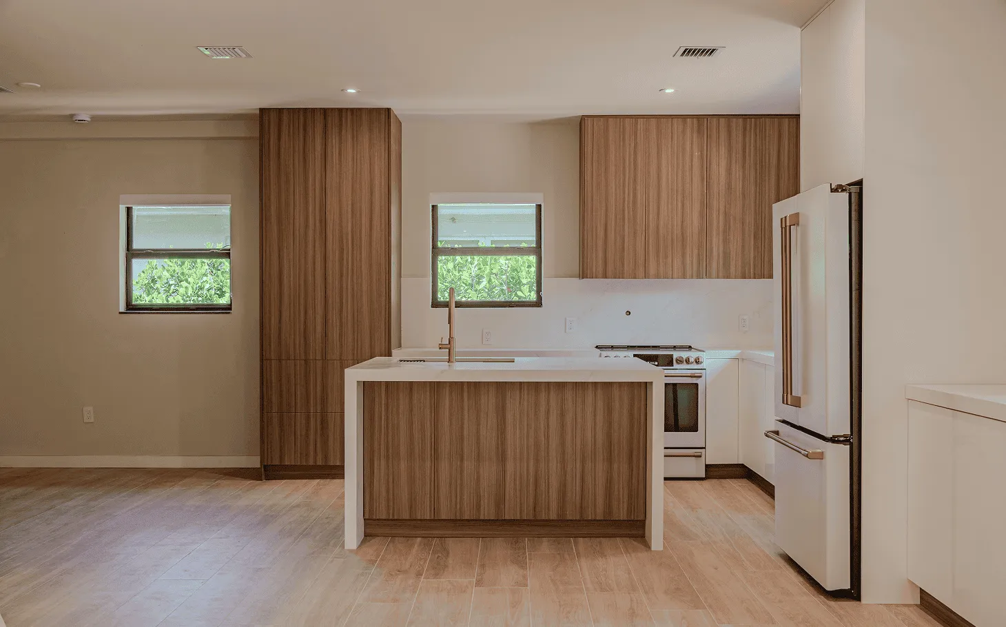 Open kitchen and living area in a renovated Axis Brickell condo, featuring marble countertops, wood cabinetry, and floor-to-ceiling windows overlooking the Miami skyline.