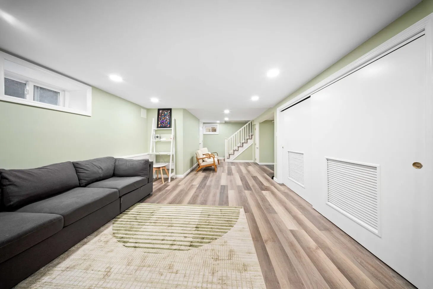 Maplewood basement living space with gray sectional, recessed lighting, and closet doors