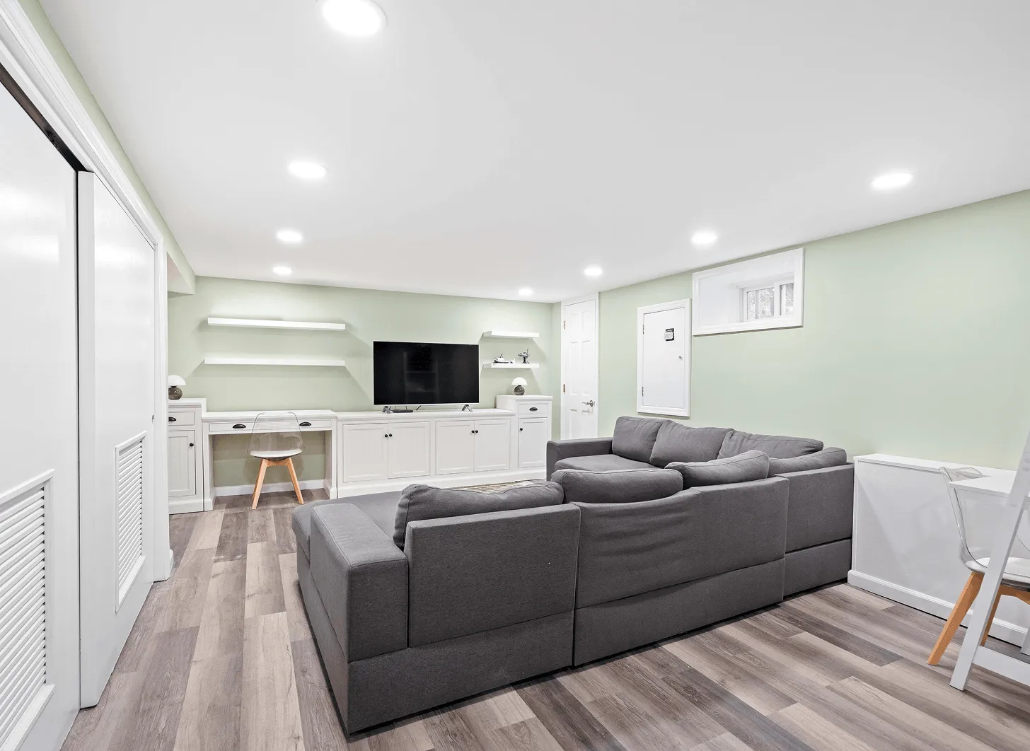 Renovated Maplewood basement living room with sage walls, sectional seating, and recessed lighting