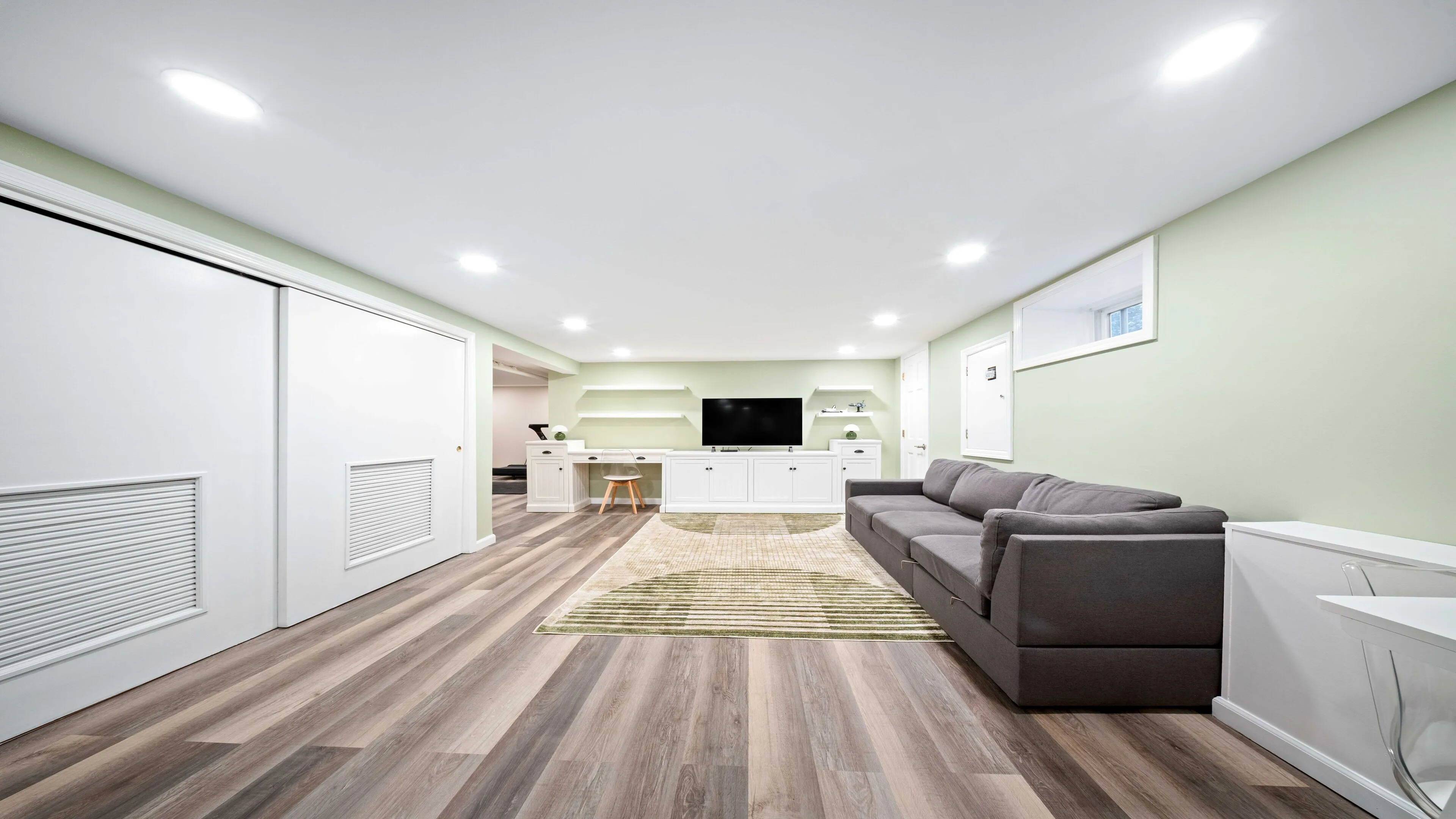 Finished Maplewood basement living area with sage walls, wood flooring, and sectional sofa