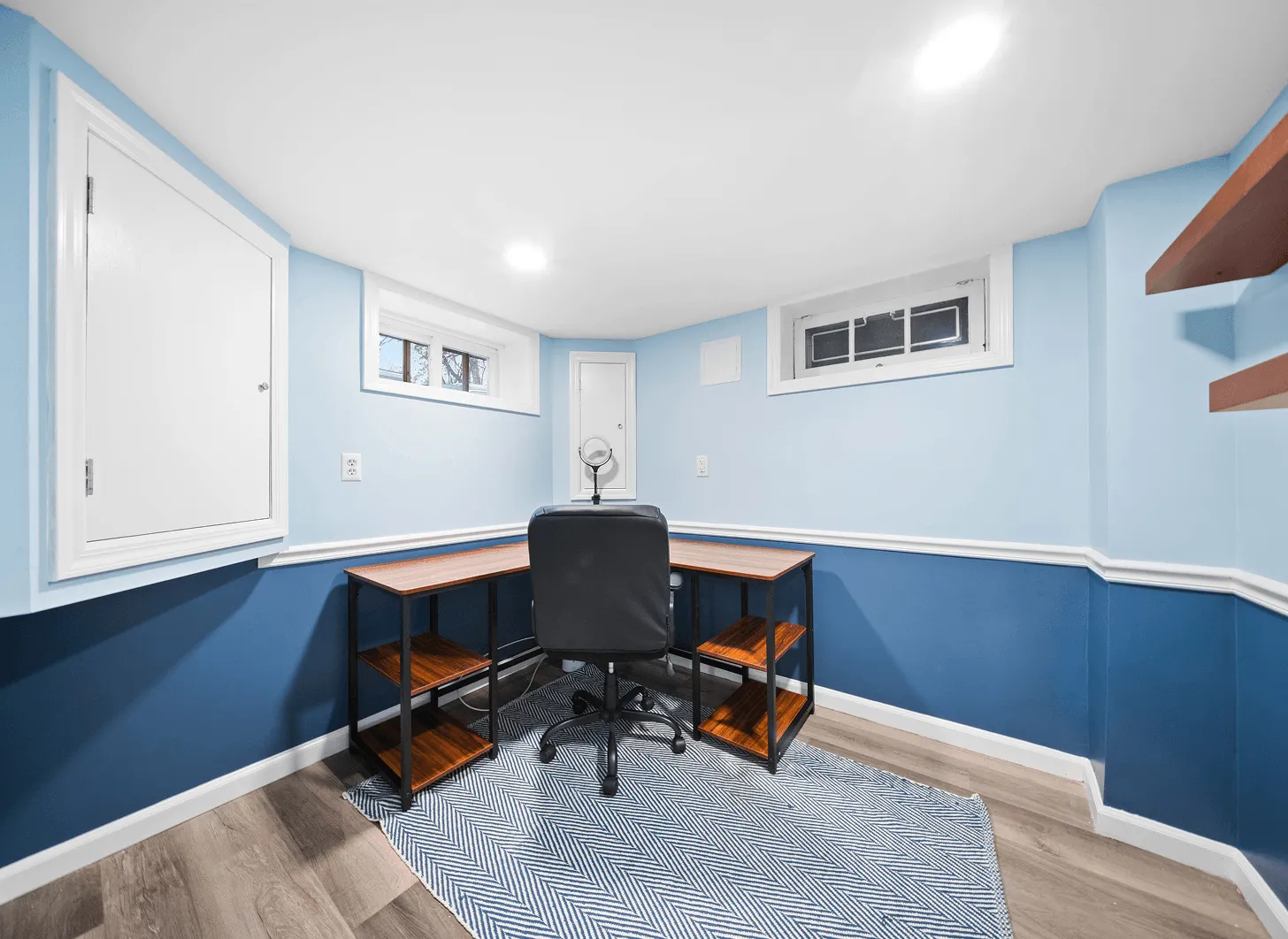 Renovated Maplewood basement office with two-tone blue walls, wood desk, and floating shelves