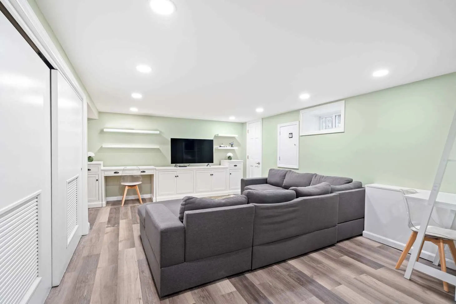 Completed Maplewood basement with sectional sofa, built-in entertainment wall, and lighting