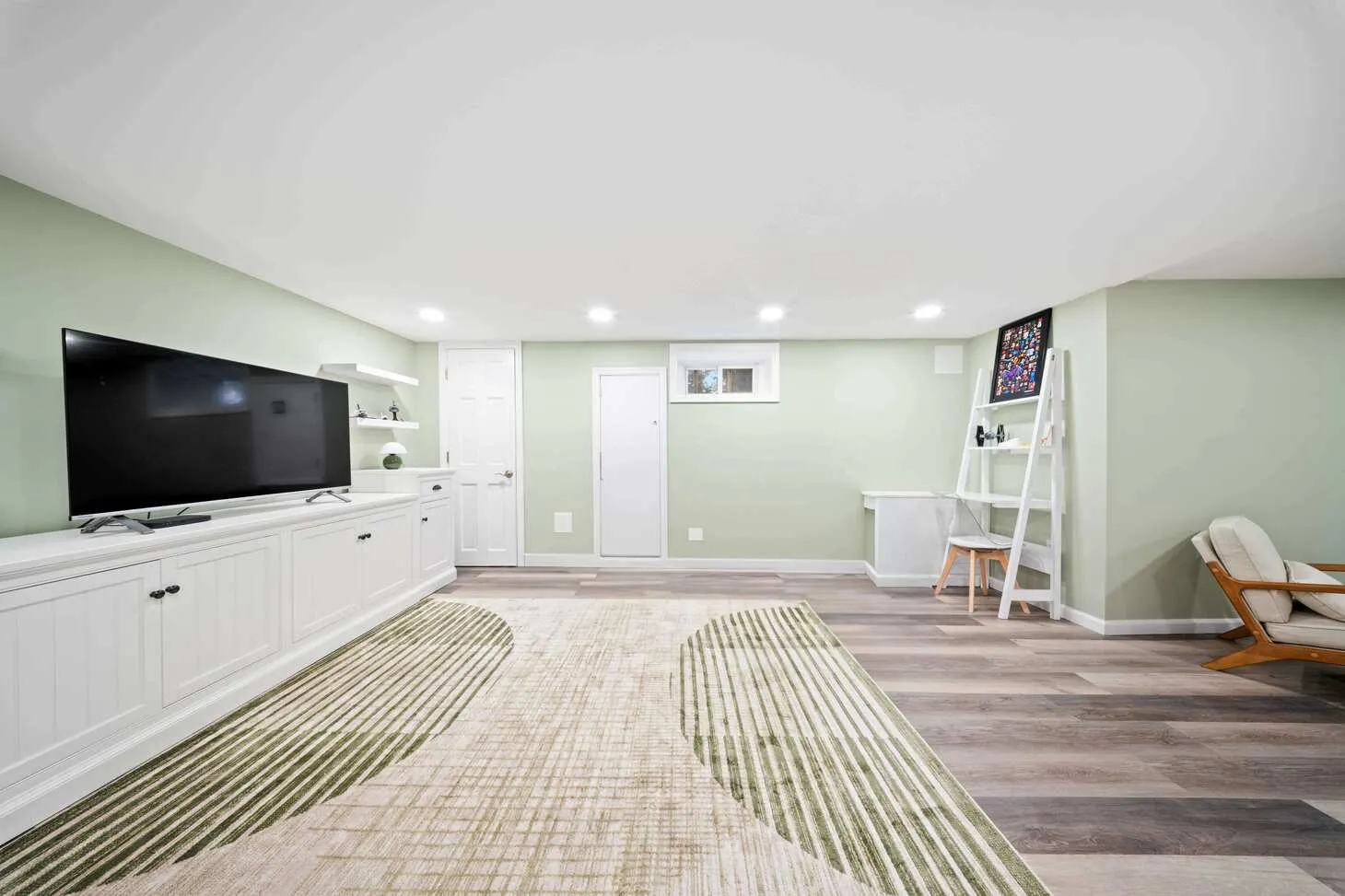 Renovated Maplewood basement with white built-in media console, desk, and geometric rug