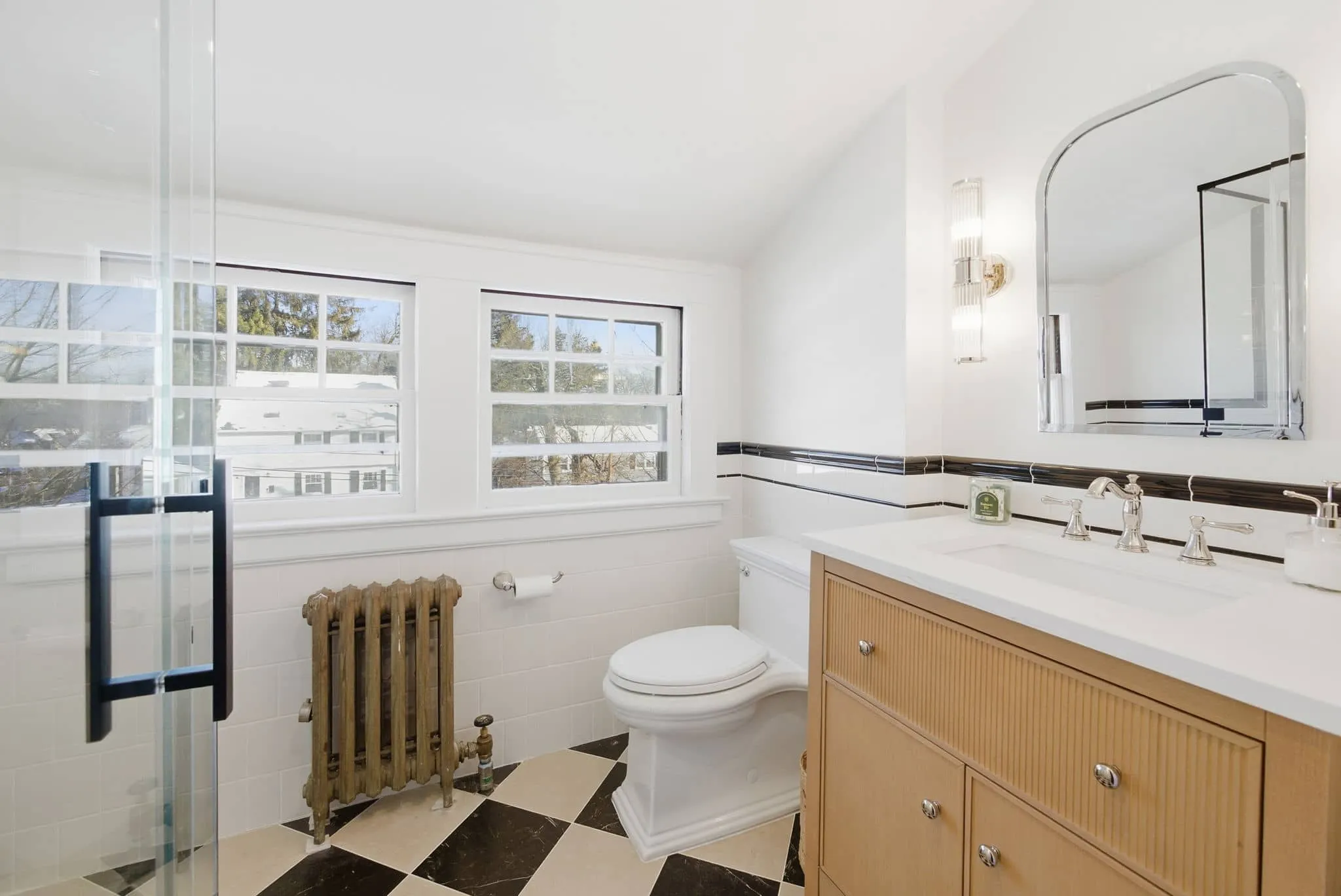 Renovated West Orange basement bathroom with deep teal wall tile, marble-look shower, and patterned flooring