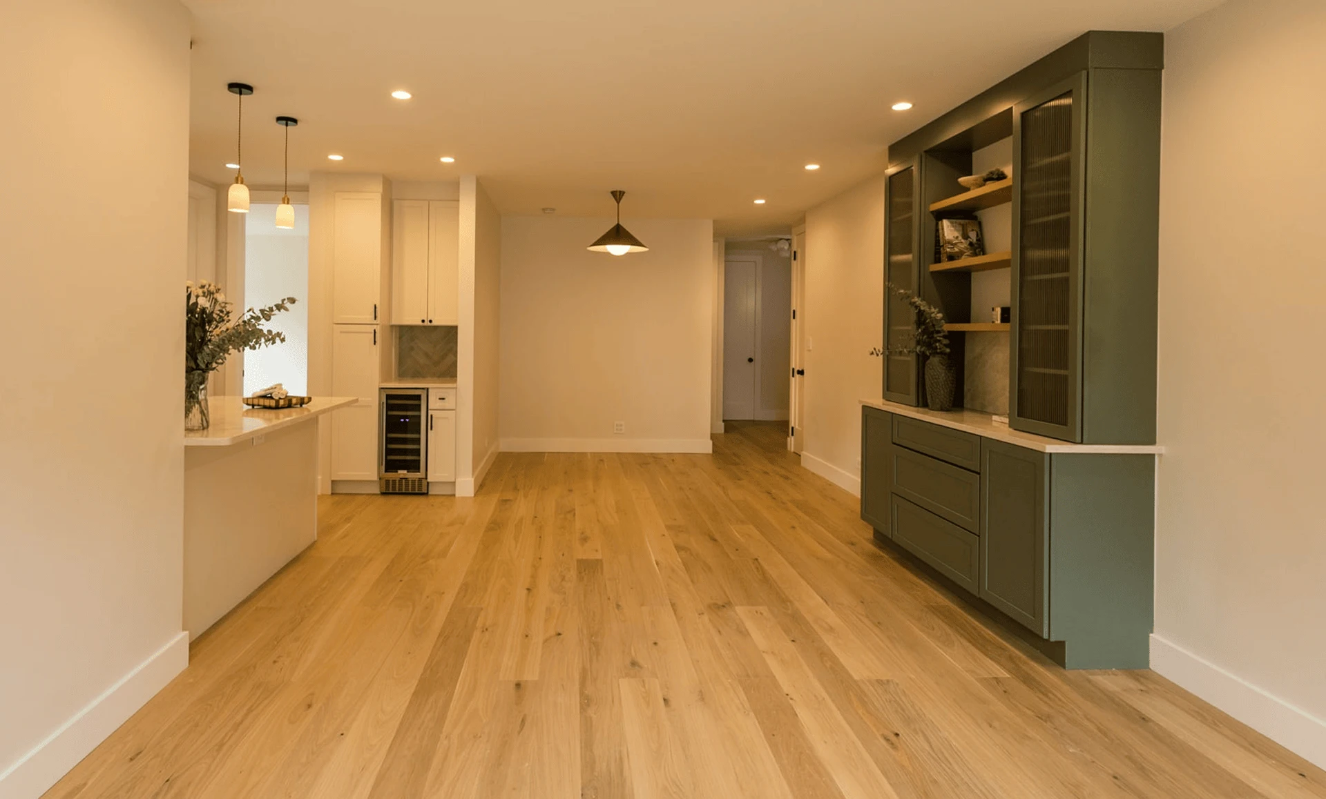 Open dining and living area with white island, wide‑plank floors, and built‑in sage‑green hutch, part of a full apartment renovation at 80 East End Avenue in Yorkville NYC