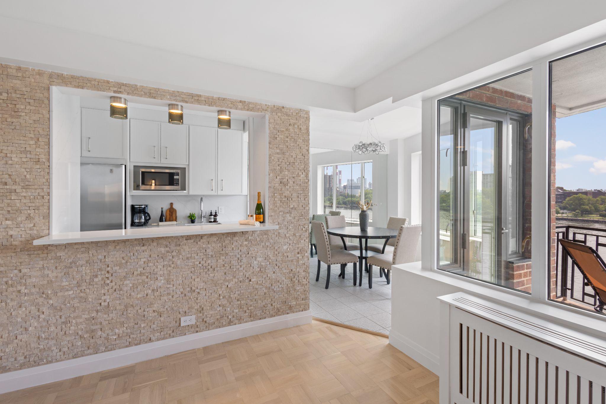 Renovated East End Avenue co-op with open kitchen pass-through, breakfast bar, and dining area overlooking the East River