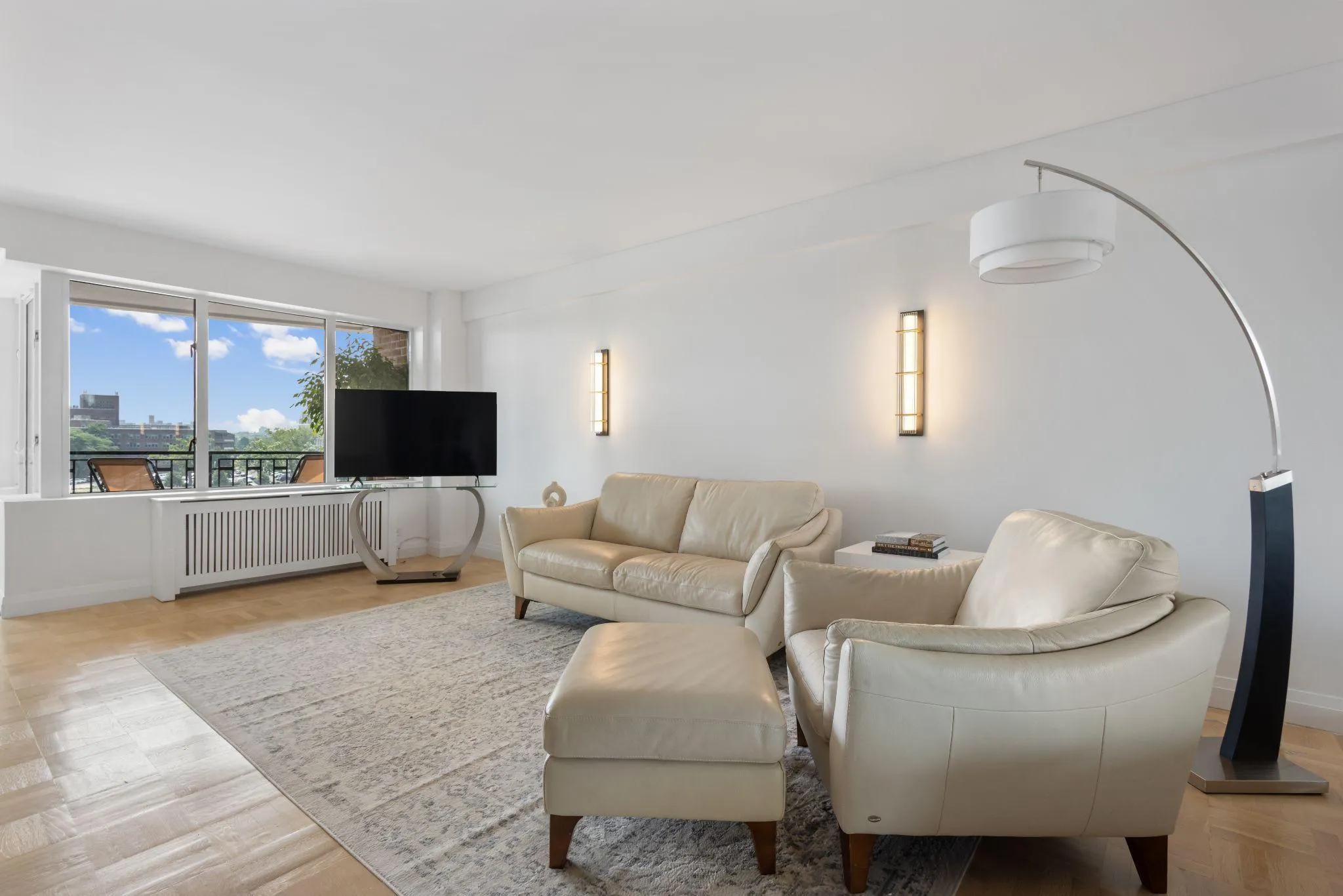Open living area with bleached white oak floors, kitchen breakfast bar, and East River balcony views