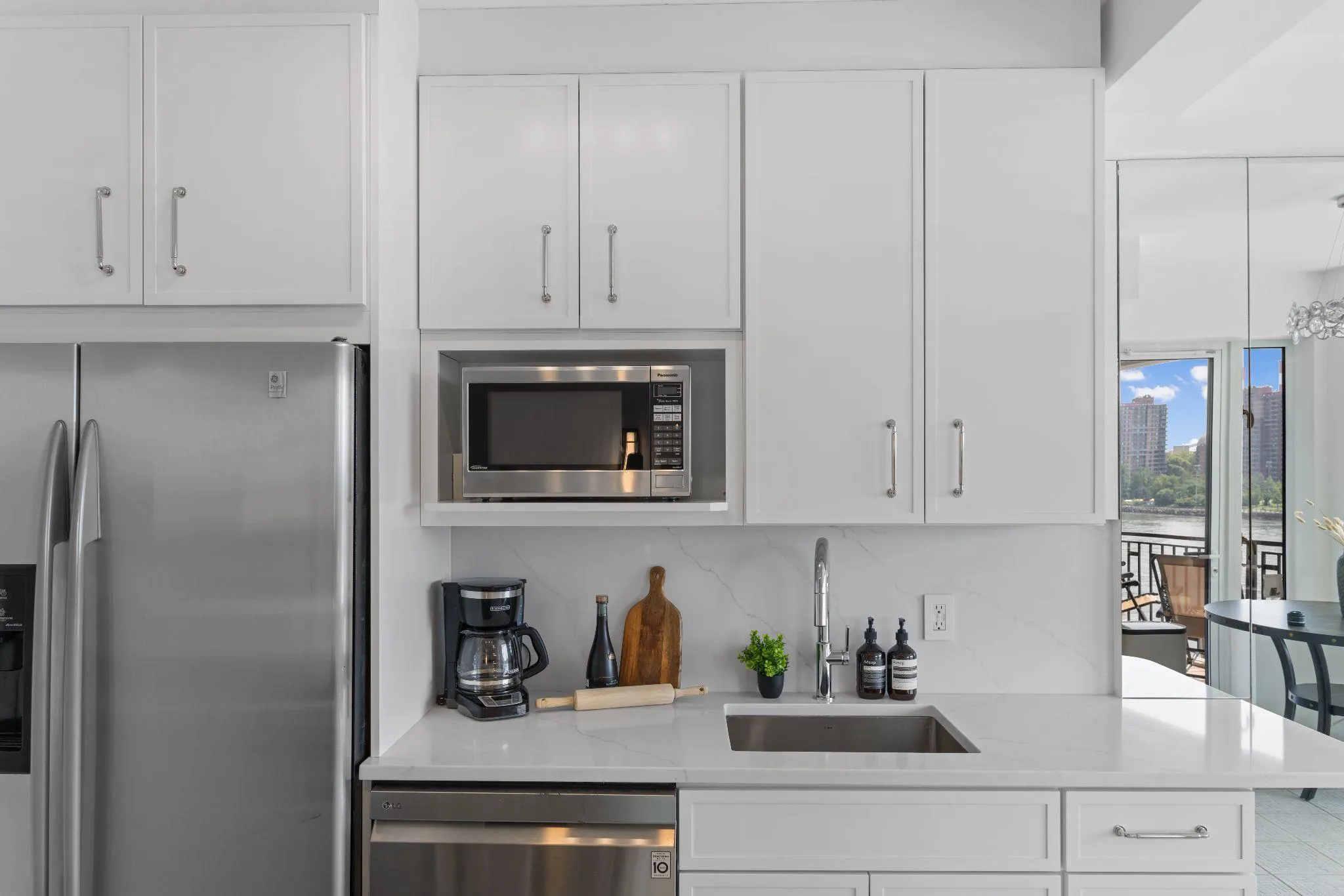 Renovated kitchen with matte white cabinets, white quartz counters, and a wide opening to the living space