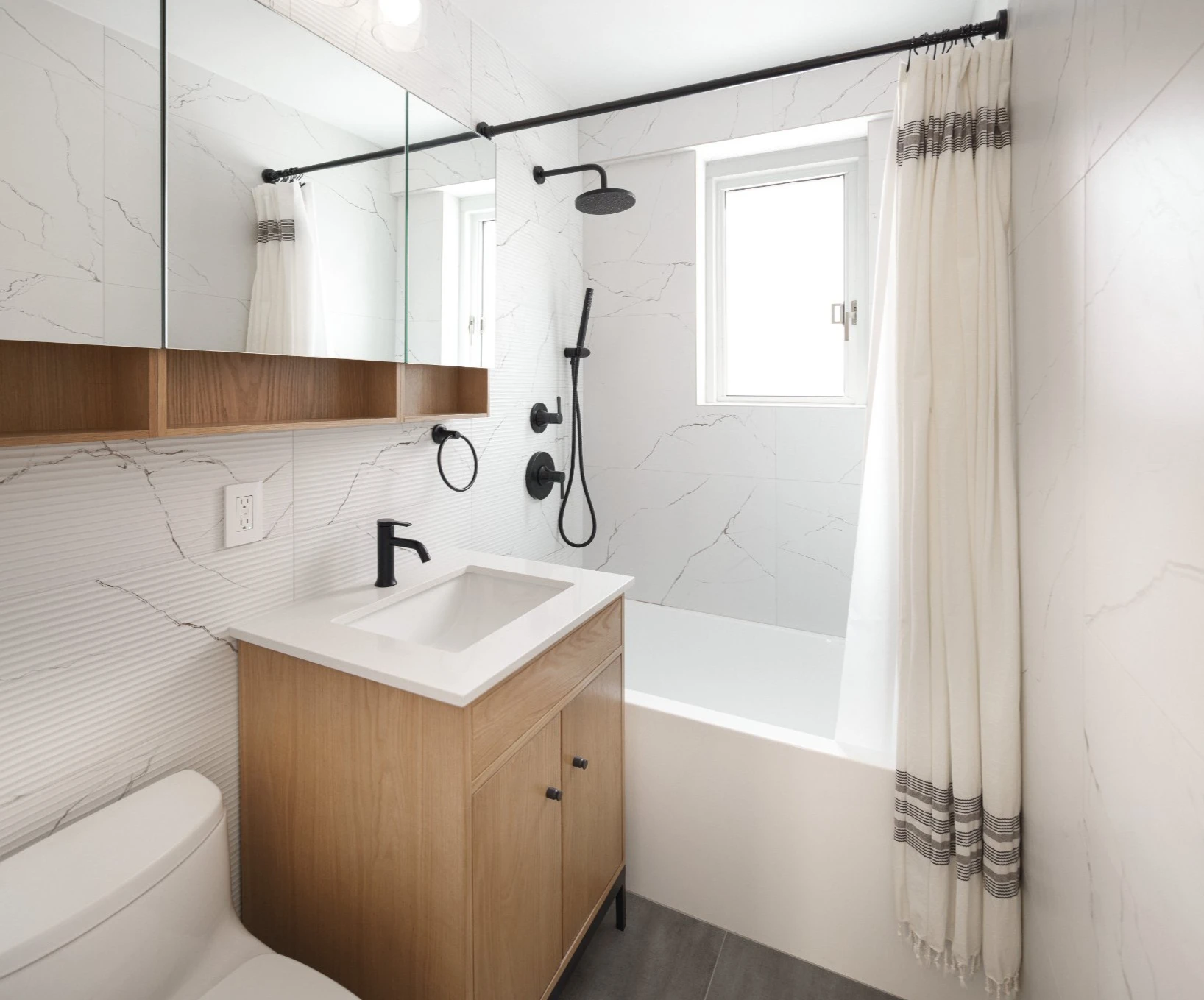 Gramercy co-op bathroom after renovation with porcelain tile and matte black fixtures
