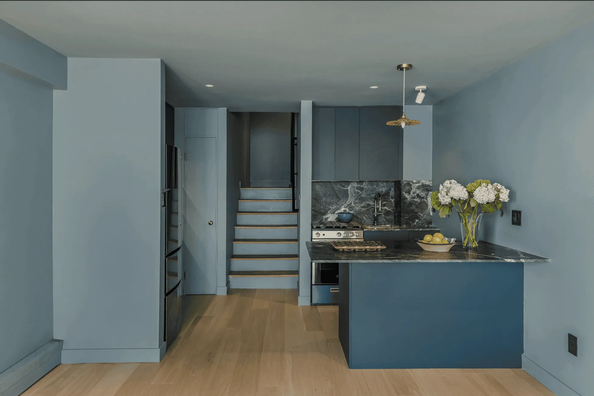 Renovated modern kitchen after with Italian Verde Alpi stone countertop and deep blue cabinetry in Jersey City