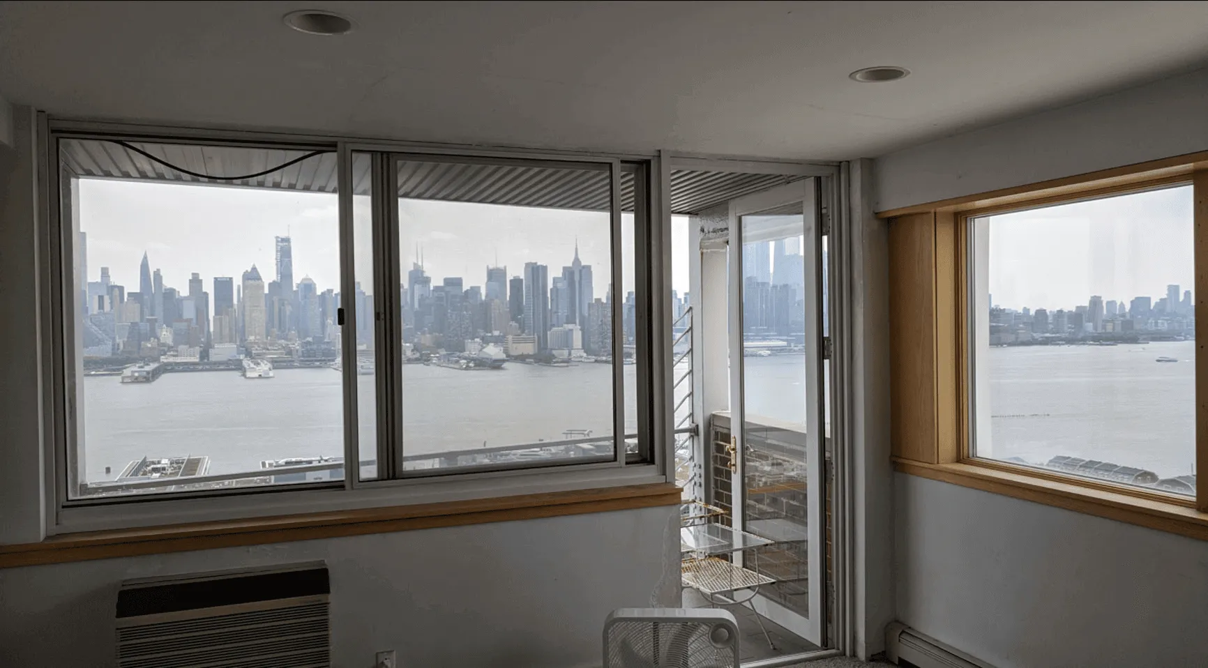 Living area before renovation in Jersey City apartment with plain white walls and basic finishes