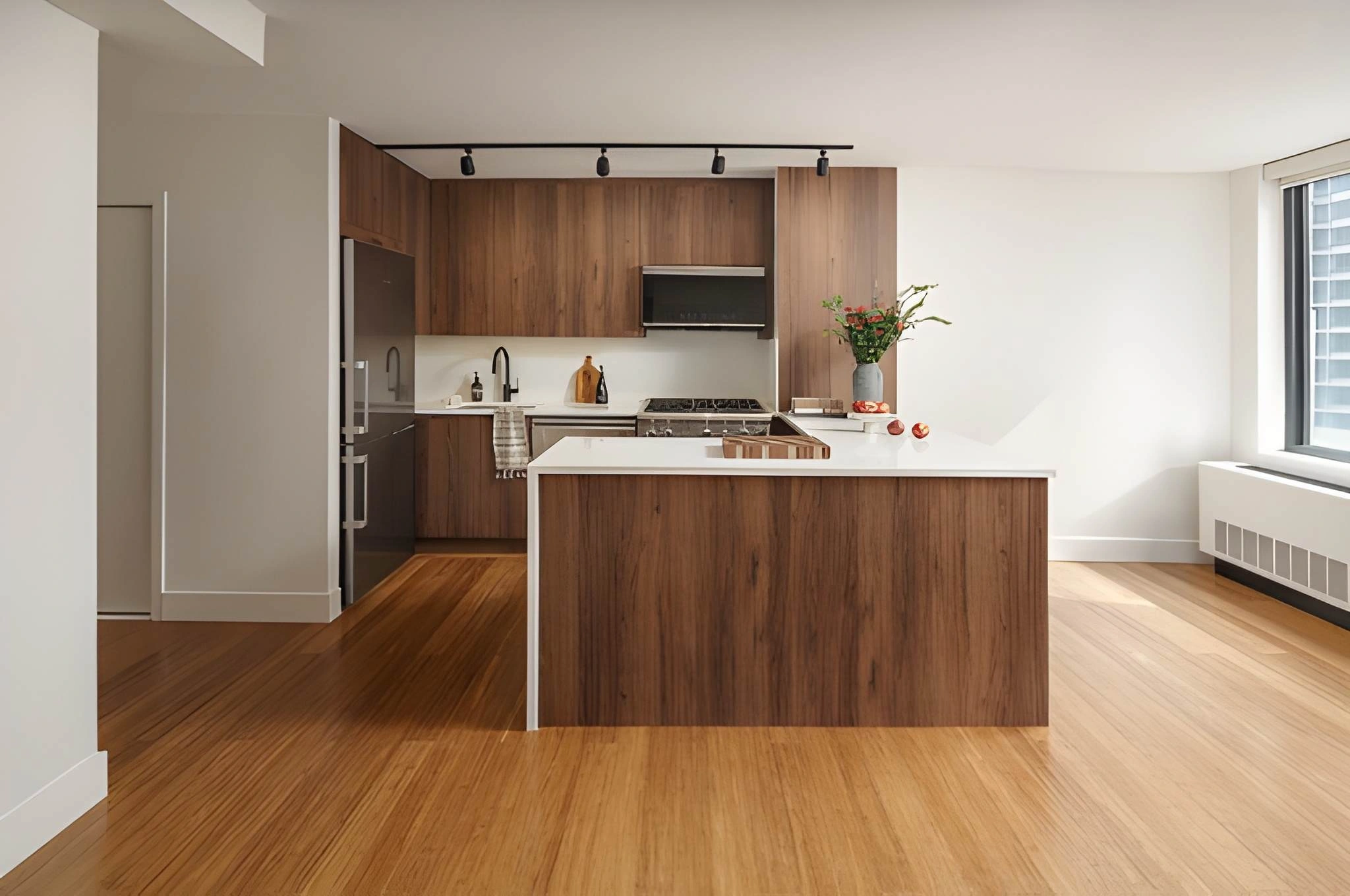 Renovated Midtown East condo kitchen with dark wood cabinetry, white waterfall island, and open living space