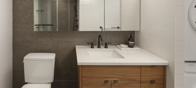 Bathroom vanity with warm wood finish and grey and white tile walls