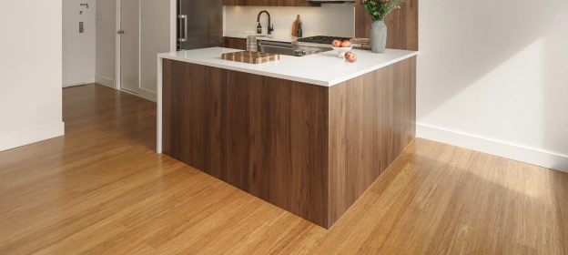 Light hardwood flooring beneath the dark wood kitchen island and white countertop
