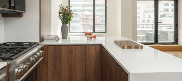 White marble kitchen countertop on a dark wood peninsula overlooking the living area
