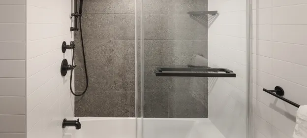 Matte black shower and tub fixtures against grey textured accent tile