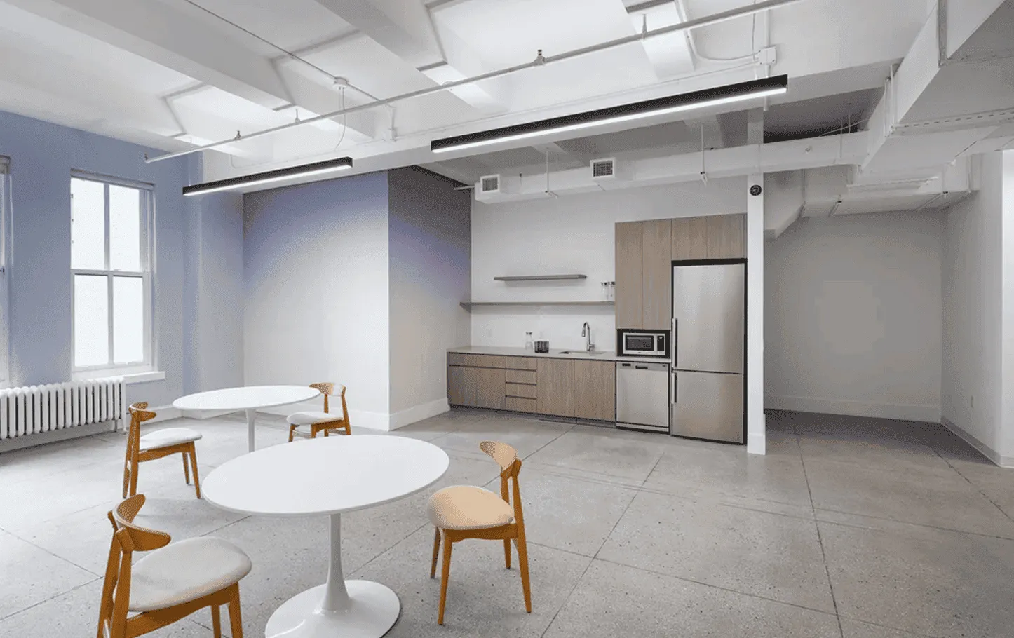 Kitchen dining and social areas in NYC tech headquarters with custom cabinetry and integrated appliances