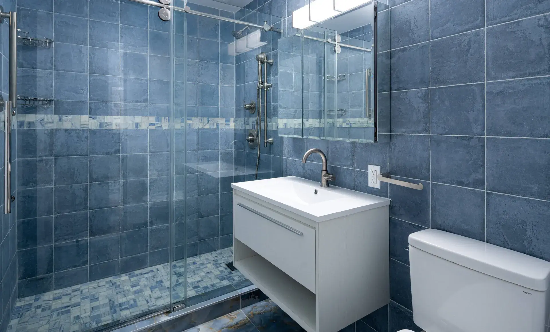 United Nations Plaza apartment primary bathroom renovation with blue tiles and chrome hardware